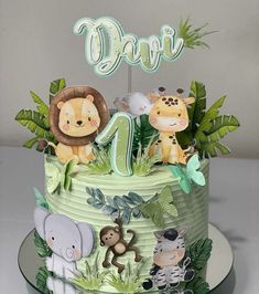 a birthday cake decorated with jungle animals and the number one is for a child's first birthday