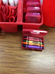 a red container filled with lots of crafting supplies on top of a wooden table