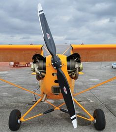 a small yellow airplane parked on top of an airport tarmac