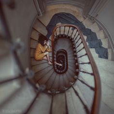 black and white photograph of spiral staircase with person sitting on the top one handrail