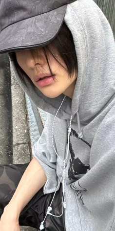 a person sitting on the ground wearing a hoodie and holding a cell phone to their ear