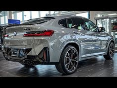 the rear end of a silver bmw suv in a showroom