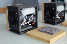 two speakers sitting next to each other on top of a white table with wires running through them