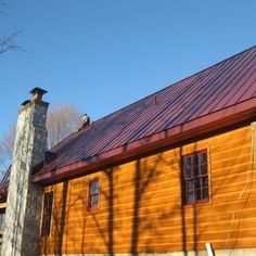 a wooden cabin with a red roof and chimney