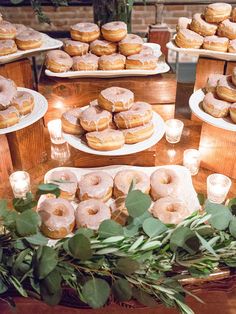 doughnuts and candles are on display in front of plates with greenery around them