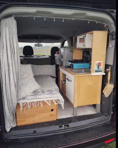 the back end of a van with a bed and desk in it