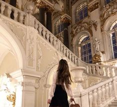 a woman is walking down the stairs in a building with white walls and gold trimmings