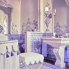 an ornate bathroom with blue and white tiles on the walls, toilet, sink and mirror