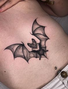 a woman's stomach with a bat tattoo on it