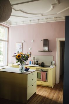 a vase filled with flowers sitting on top of a counter next to a stove top oven