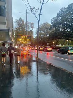 people walking down the street in the rain with umbrellas and signs on them that read happy marathon today