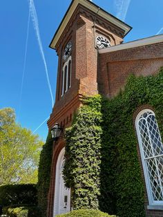 an old brick building with ivy growing on it's side and a clock tower