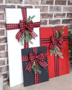 three christmas presents are sitting on a shelf next to a brick wall and decorated with greenery