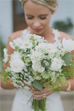 a woman holding a bouquet of white flowers