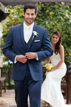 a man in a blue suit standing next to a woman