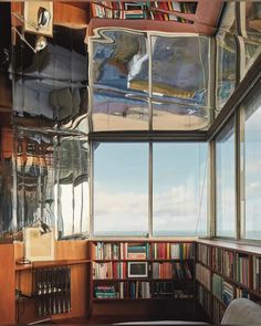 a room with bookshelves and windows that look out onto the ocean from it