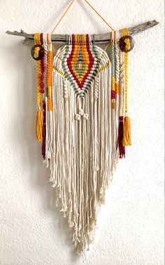 the wall hanging is decorated with different colored beads and tassels, which are hung on a white wall