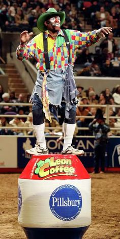 a man dressed in clown attire standing on top of a ball at a rodeo event