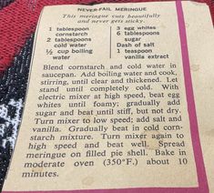 an old recipe book laying on top of a red blanket