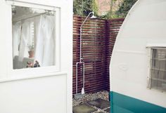 an rv parked next to a wooden fence with a window in the middle and a shower head mounted on it's side