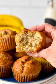 a person holding a muffin in front of some bananas on a blue and white plate