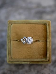 an engagement ring in a velvet box on top of a carpeted surface, with one diamond set in the middle