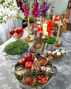 a table topped with bowls filled with fruit and vegtables next to candles