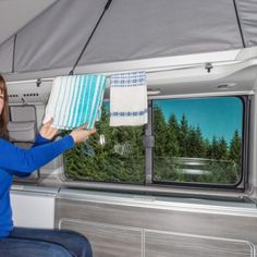 a woman sitting in the back of a camper holding up a piece of paper