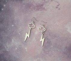 a pair of silver earrings with lightning bolt charms hanging from them on a marble surface