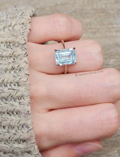 a person wearing a ring with an aqua blue topazte in it's center