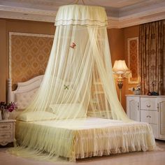 a bed with a white canopy over it in a bedroom next to a dresser and lamp