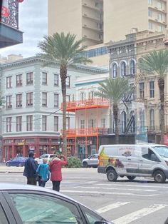 people are walking across the street in front of some buildings