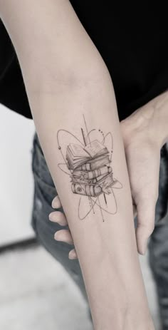 a woman with a tattoo on her arm holding a stack of books in her hand