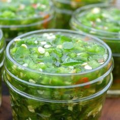 several jars filled with green vegetables on top of a wooden table