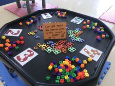 a black tray topped with lots of different colored toy blocks and a sign that says can you match the numbers place to the correct letters?