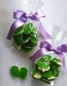 two bags filled with green and white candies next to purple ribboned bows on top of each bag