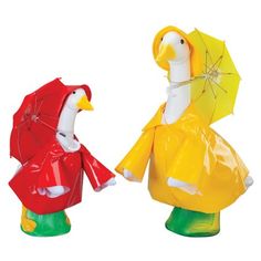 two plastic ducks wearing raincoats and holding umbrellas, one in the shape of a bird