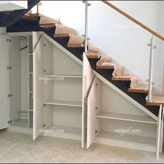 an empty room with some shelves under the stairs and a closet underneath the stair case