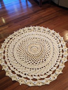 a crocheted doily is laying on the floor in front of a couch