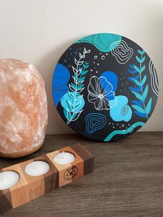 two candles sitting on top of a wooden table next to a plate and candle holder