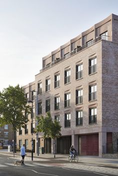 two bicyclists ride past an apartment building