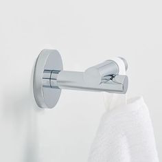 a white towel hanging on the wall next to a toilet paper roll and a chrome faucet