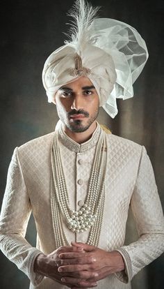 a man wearing a turban and pearls is posing for the camera with his hands in his pockets