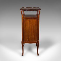 an old fashioned wooden cabinet with a mirror on the top and shelf below it, against a gray background