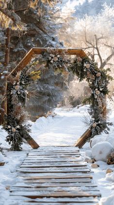 a wooden walkway covered in snow next to trees