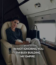 a woman sitting in an airplane holding a coffee cup and looking at the camera with a caption that reads, i'm not ignoring you, i'm busy building my empire