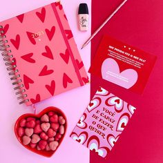 valentine's day stationery with heart shaped candies, notebook and pen on pink background