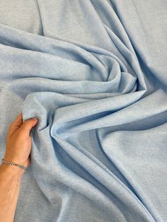 a person's hand on top of a light blue sheet that is rolled up