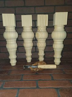 three white candlesticks and a piece of bread on a brick floor in front of a brick wall