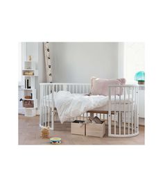 a white crib with two boxes underneath it and a blanket on the floor next to it